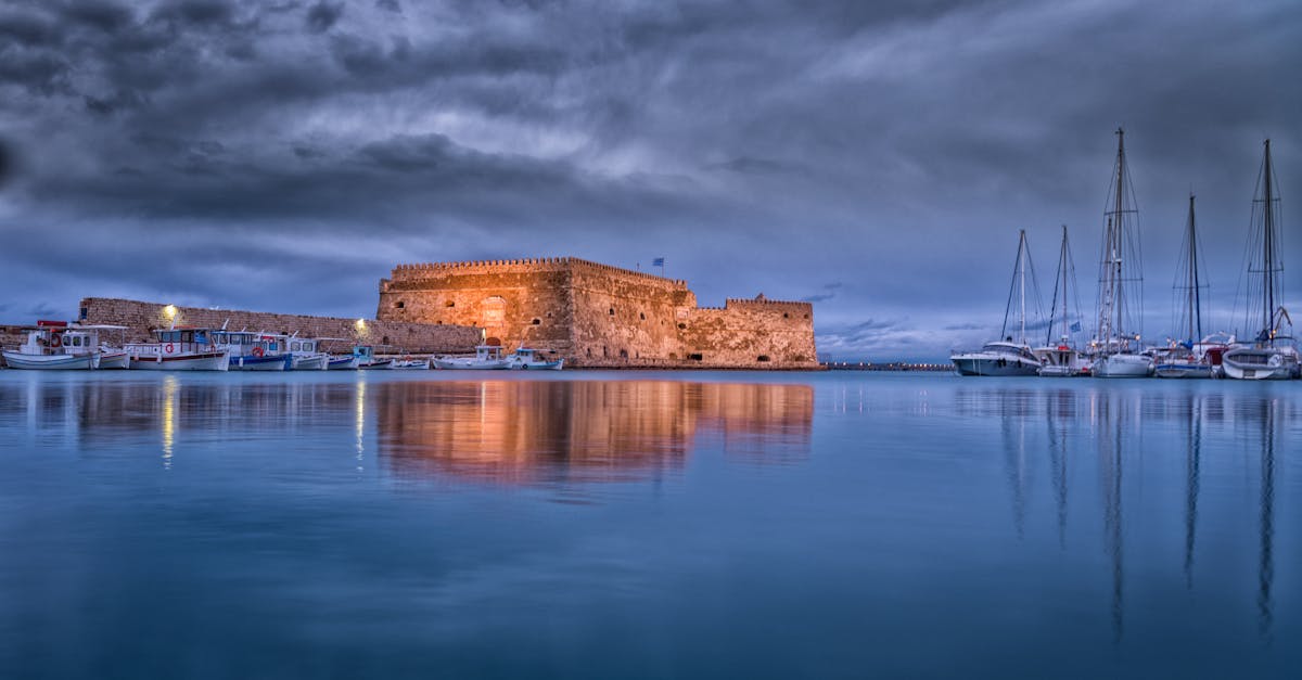 Majestic view of Koules Fortress reflected in calm waters at Heraklion harbor during twilight.