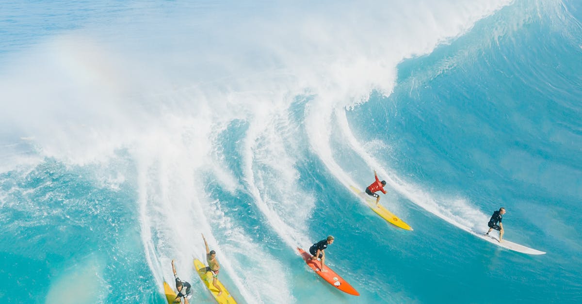 Dynamic aerial photo capturing surfers conquering massive waves in vibrant blue Hawaiian waters.